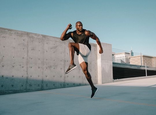 man in sports gear doing a high knee up move