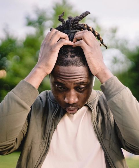 A man standing outside looking stressed with his hands in his hair