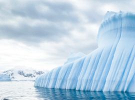 the side of a giant iceberg in bright blue water