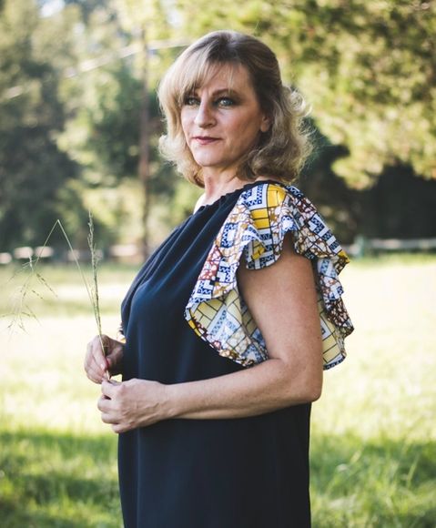 Mature women standing in a natural setting holding a piece of grass in her hands