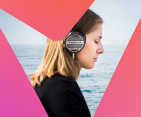 woman with eye closed listening to headphones in front of the sea